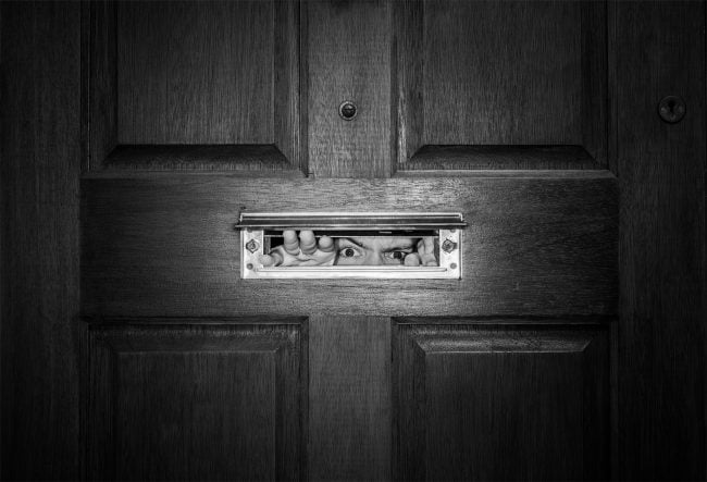 man peeping through mailbox slot