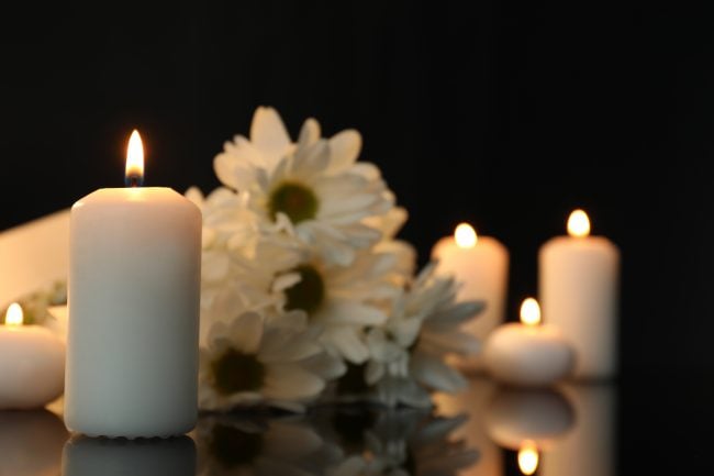 White chrysanthemum flowers and burning candles on black mirror