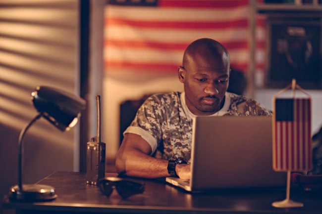 African american soldier using a laptop while deployed in a military base