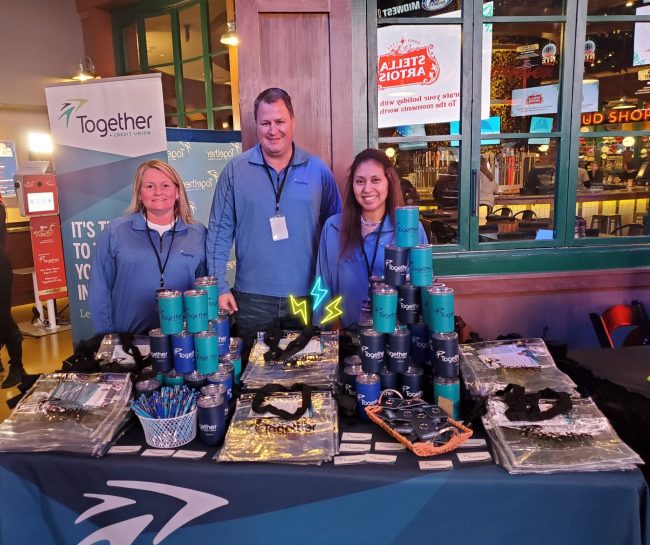 Skube with Together CU employees Christine Worley (left) and Juanita Median (right) volunteering at Deck the Hall Ball, a community event hosted by Audacy at Ballpark Village in St. Louis in 2019