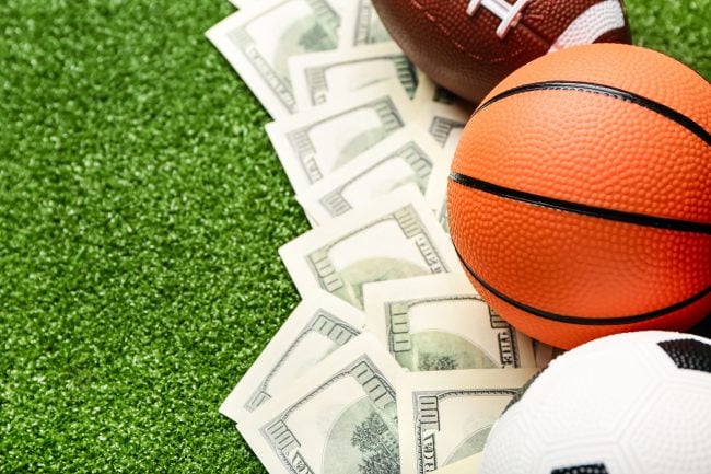 Money and sports balls on green turf background