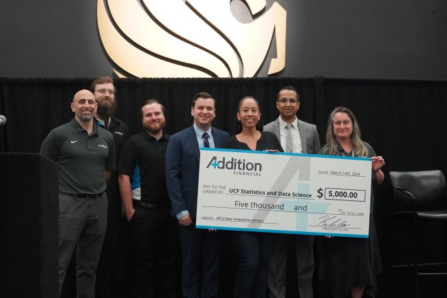 Hayden Hampton, fourth from left, receives his grand-prize check from Addition Financial Business Intelligence department team members (from left to right) Jason Mizrahi, Kyle Parcels, Tristan Couple, Lauren Solivan, Sital Nayee and Kristen Karlen at UCF's Big Data Analytics Symposium