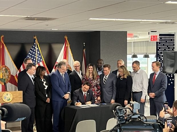 Several credit union leaders gather around Gov. Ron DeSantis as he signs HB 989 on Thursday, May 2, 2024. Credit/LSCU