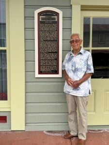 Gilbert Awong next to building plaque