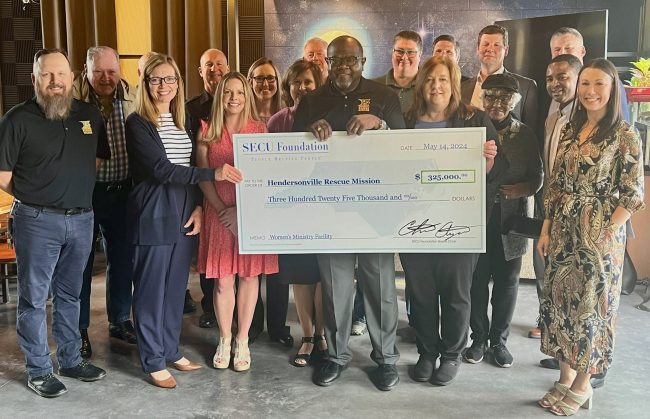 Holding check from left to right: HRM Board Member and SECU Hendersonville Branch Advisory Board Member Laura Simpson; HRM CEO Reverend Anthony McMinn; and SECU Regional SVP Kim Hollifield, surrounded by SECU and SECU Foundation representatives