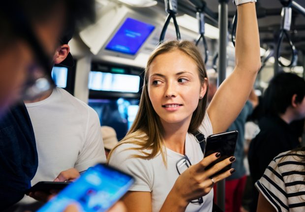 Young woman holding a smartphone while riding the subway