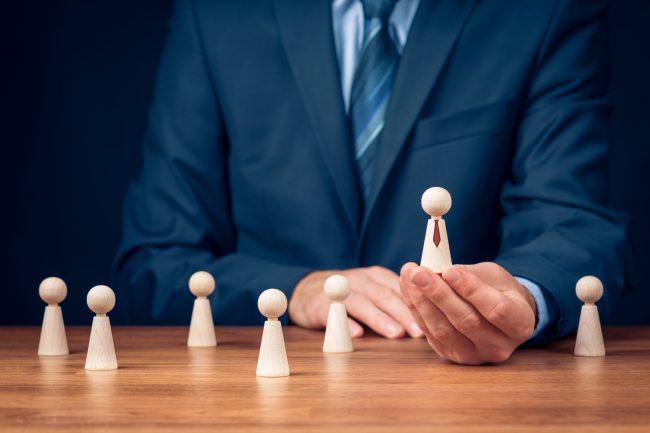 businessman selects wooden figure out of group