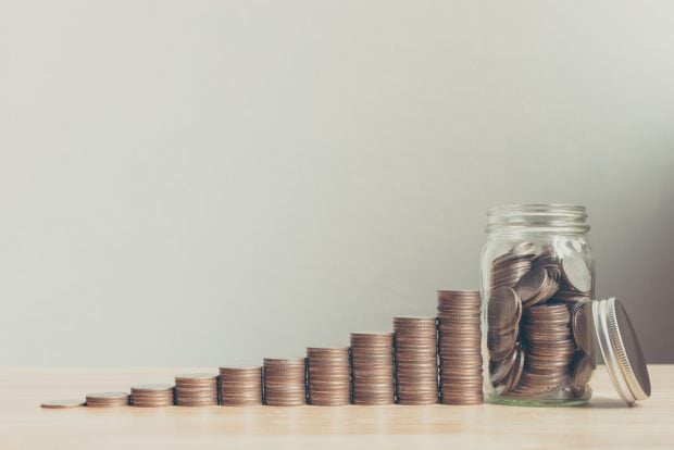 Row of coins growing higher with each stack until it reaches a glass jar with many coins inside