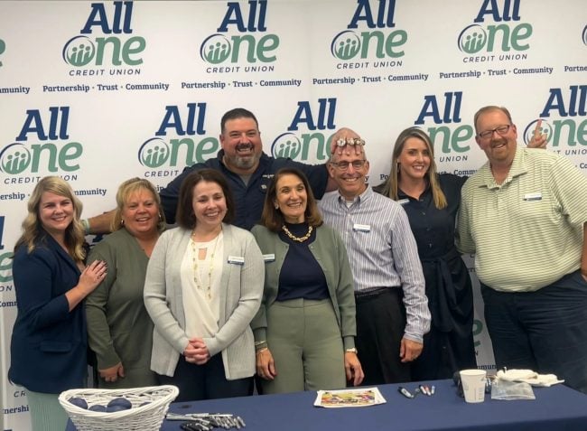 Retired NFL guard Joe Andruzzi (in back row) with All One CU team members at a celebration of the credit union's new name earlier in October.